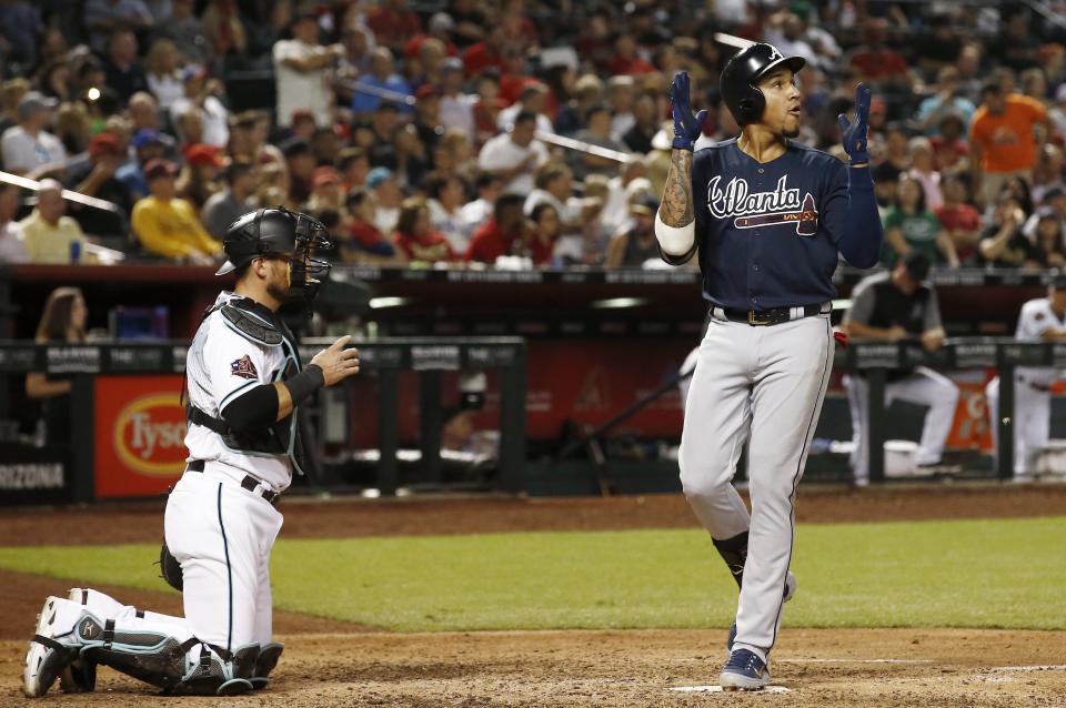 Atlanta Braves' Johan Camargo, right, claps as he arrives at home plate after hitting a home run as Arizona Diamondbacks catcher Jeff Mathis, left, pauses during the sixth inning of a baseball game Thursday, Sept. 6, 2018, in Phoenix. (AP Photo/Ross D. Franklin)