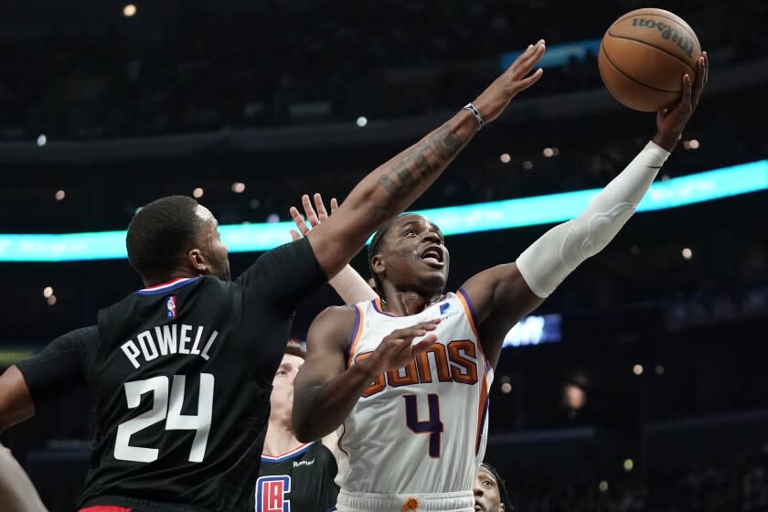 Phoenix Suns guard Aaron Holiday, right, shoots as Los Angeles Clippers forward Norman Powell defends