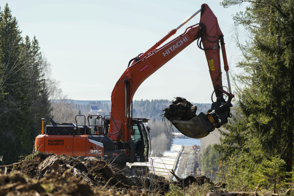 An excavator works at construction site of the border barrier fence between Finland, right, and Russia near Pelkola border crossing point in Imatra, south-eastern Finland, Friday, April 14, 2023. (AP Photo/Sergei Grits)