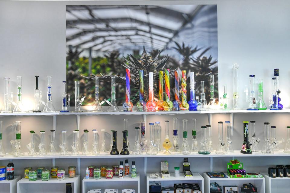 A photo of medical marijuana plants is seen behind water pipes on display in Peace Avenue Smokeshop in Port St. Lucie, one of the original stores on the Treasure Coast selling CBD products, along with American-made glass pipes, papers, wraps, vaporizers, custom pieces, and glass accessories. "There's a dispensary across the street where my customers can walk over and get medical marijuana, come over here and purchase the accoutrements and hand choose what they want accordingly," said Chad Rowland, owner of Peace Avenue Smokeshop.