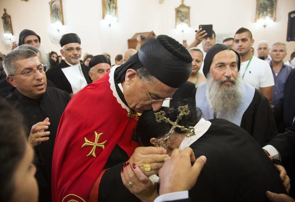 Maronite Patriarch Rai kisses the head of a worshipper during a visit to the Maronite church in Jaffa