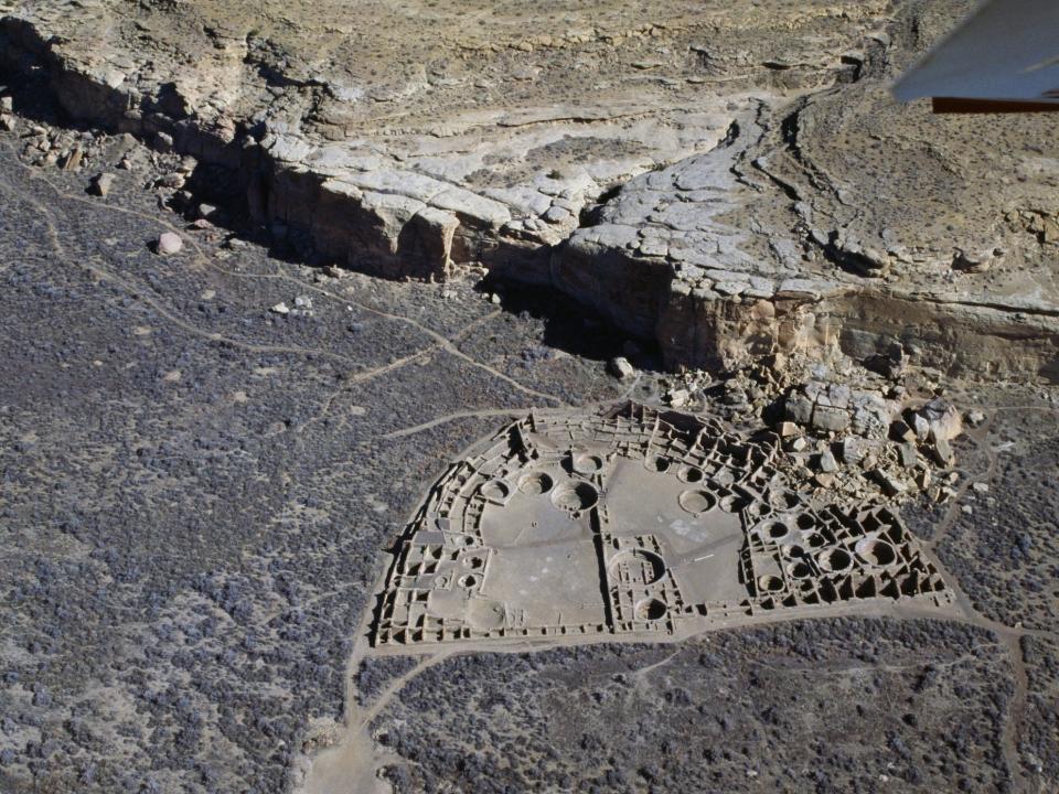 An aerial view of Pueblo Bonito shows the ruins of a semi circular settlement.