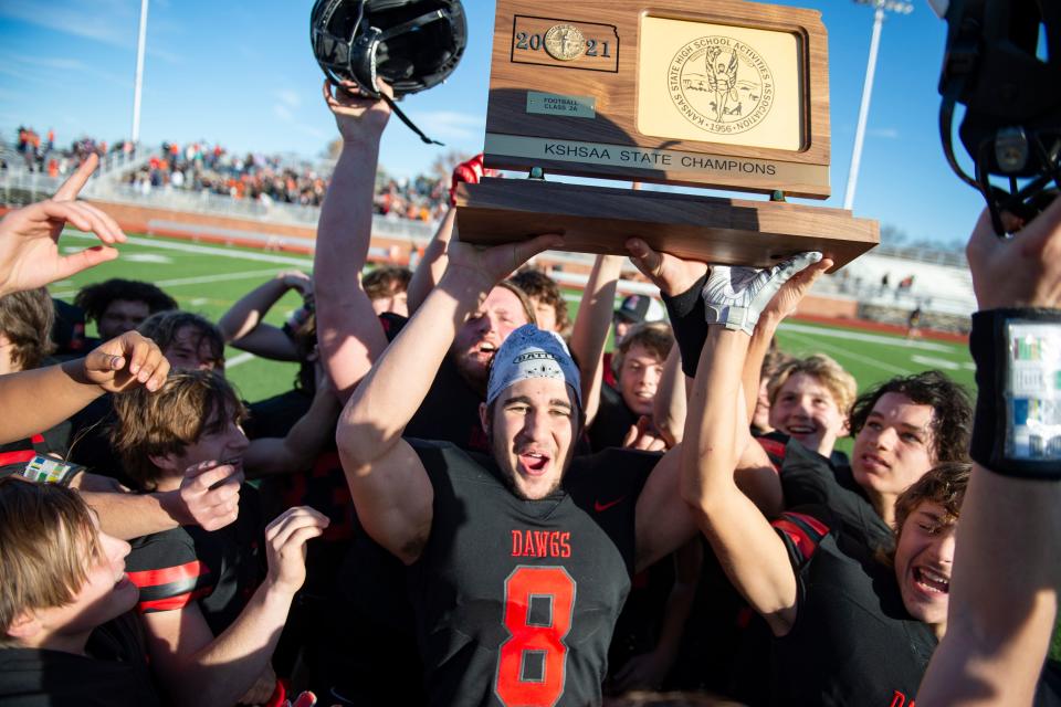 Rossville Raphael Cooney (8) holds up the plaque after beating Beloit 35-16 on Saturday in Salina.