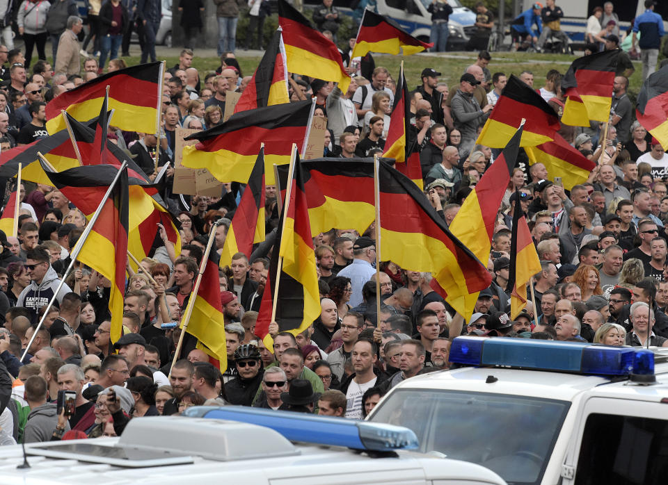 People wave with German national flags during a demonstration in Chemnitz, eastern Germany, Friday, Sept.7, 2018, after several nationalist groups called for marches protesting the killing of a German man two weeks ago, allegedly by migrants from Syria and Iraq. (AP Photo/Jens Meyer)