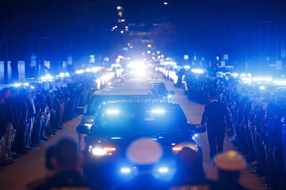 Chicago police officers stand along West Harrison Street as the the body of an officer who was fatally shot is brought to the Cook County medical examiner.