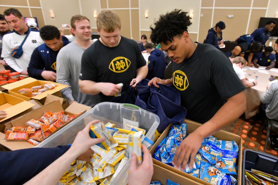 Notre Dame tight end Holden Staes (right) packs food in a backpack on Dec. 28, 2022 at the Omni Amelia Resort Convention Center as part of charitable work done by players in the 2022 TaxSlayer Gator Bowl for Blessings in a Backpack, one of the primary charities helped by the Constellation Furyk & Friends tournament.