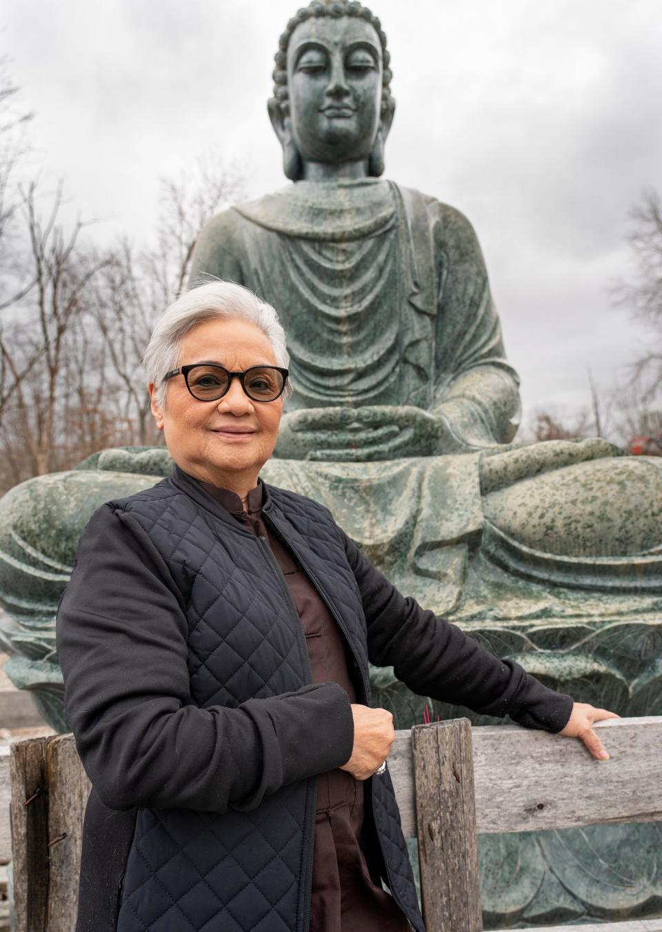 Deborah Nguyen, a member of the Phap An Temple, stand by a large Buddha in the sculpture garden Thursday, Feb. 9, 2023 at Phap An Temple.