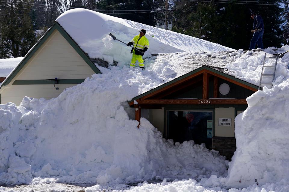 A worker clears snow off the roof of Skyforest Elks Lodge after a series of storms, in Rimforest, Calif., on March 8.