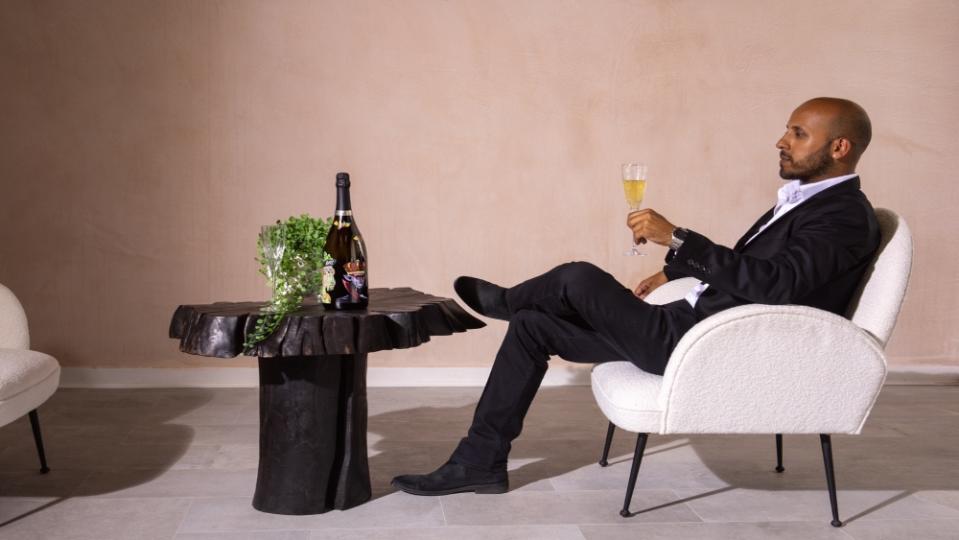 Shammi Shinh sitting with limited-edition bottle - Credit: Champagne Avenue Foch