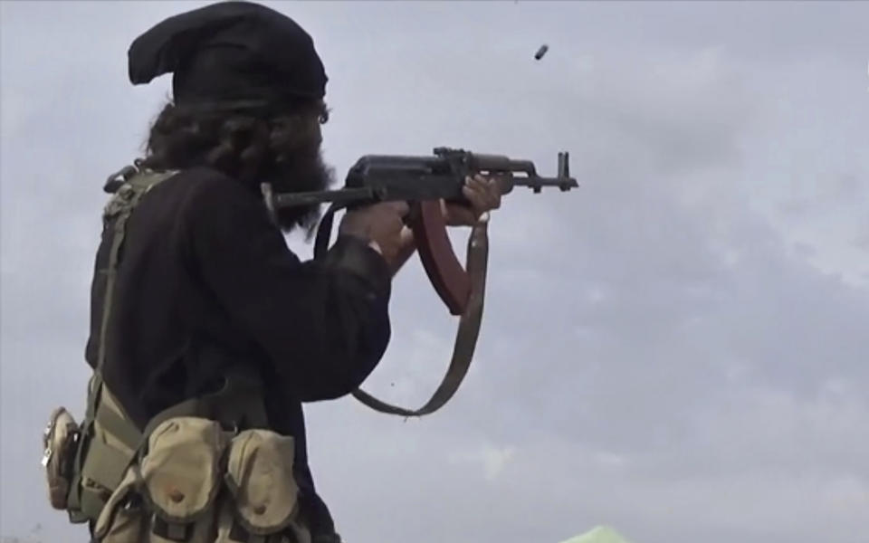 FILE - This file frame grab from video posted online Monday, March 18, 2019, by the Aamaq News Agency, a media arm of the Islamic State group, shows an IS fighter firing his weapon during clashes with the U.S.-backed Syrian Democratic Forces (SDF) fighters, in Baghouz, Syria. The SDF fighters who drove the Islamic State from its last strongholds called Monday, March 25, 2019, for an international tribunal to prosecute hundreds of foreigners rounded up in the nearly five-year campaign against the extremist group. (Aamaq News Agency via AP, File)