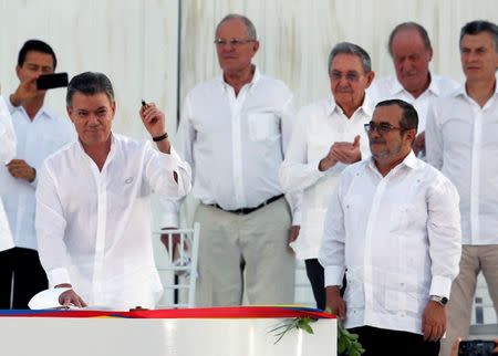 Colombian President Juan Manuel Santos (L) holds a pen made from a bullet before signing an accord ending a half-century war that killed a quarter of a million people, as Marxist rebel leader Rodrigo Londono (R), known by his nom de guerre Timochenko, looks on in Cartagena, Colombia, September 26, 2016. REUTERS/John Vizcaino