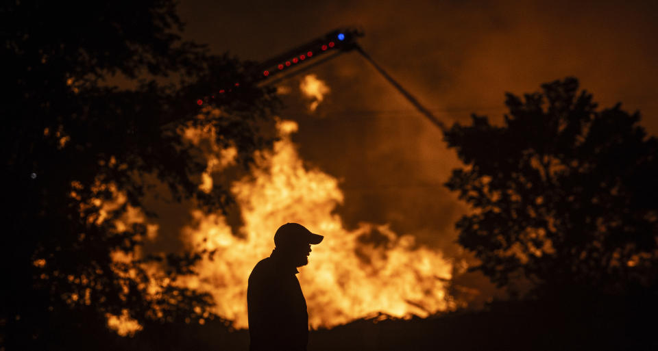 A large fire broke out at Evergreen Recycle in Park City, Kan., on Sunday, June 23, 2024. The facility recycles wooden pallets and it's the second time in the last two years a large fire has occurred at Evergreen Recycle. On Tuesday, a helicopter from the Kansas Air National Guard was dropping water over the fire that continues to burn. Sedgwick County Fire Marshal Brad Crisp said during a Tuesday morning press conference that no cause for the fire has been determined. (Travis Heying/The Wichita Eagle via AP)