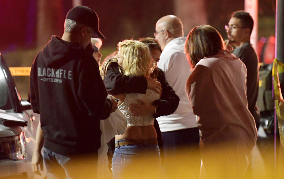 FILE - In this Thursday, Nov. 8, 2018, file photo, people comfort each other as they stand near the scene in Thousand Oaks, Calif., where a gunman opened fire Wednesday, Nov. 7, inside a country dance bar crowded with hundreds of people on "college night," wounding multiple people including a deputy who rushed to the scene. The 12 people killed in a mass shooting and gun battle at the Southern California country-western bar a year ago have been remembered in a public park memorial called The Healing Garden. The garden was to be dedicated Thursday, Nov, 7. (AP Photo/Mark J. Terrill, File)