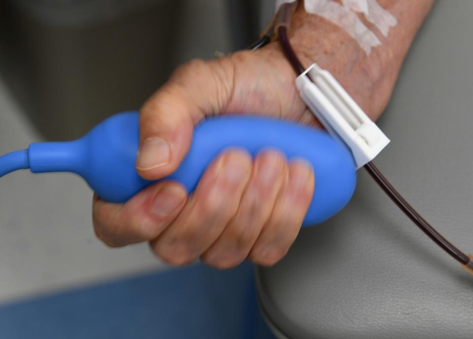 Richard Pecor squeezes a stress pump while donating plasma at OneBlood donation center.