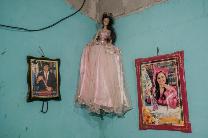 A doll hangs on the wall, with a framed photo on either side.