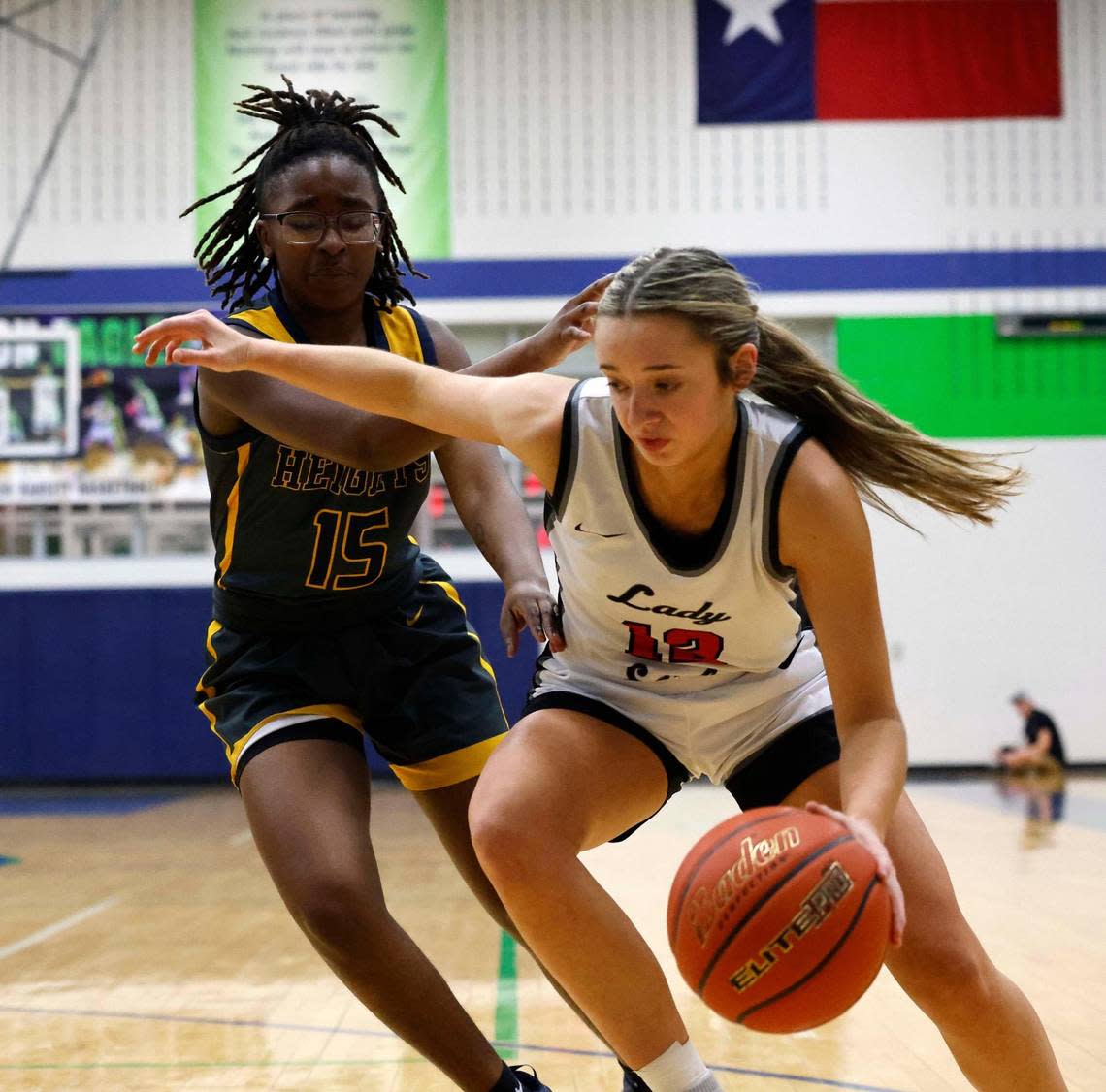 Argyle guard Gabby Campbell (12) turns the corner on Arlington Heights forward Kiana Woods (15) during the first period of a UIL Conference 5A Region 1 Area Round Championship basketball game at Haslet Eaton High School in Fort Worth, Texas, Friday, Feb. 16, 2024.