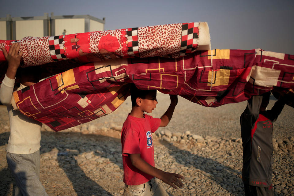 Newly internally displaced boys carry mattresses