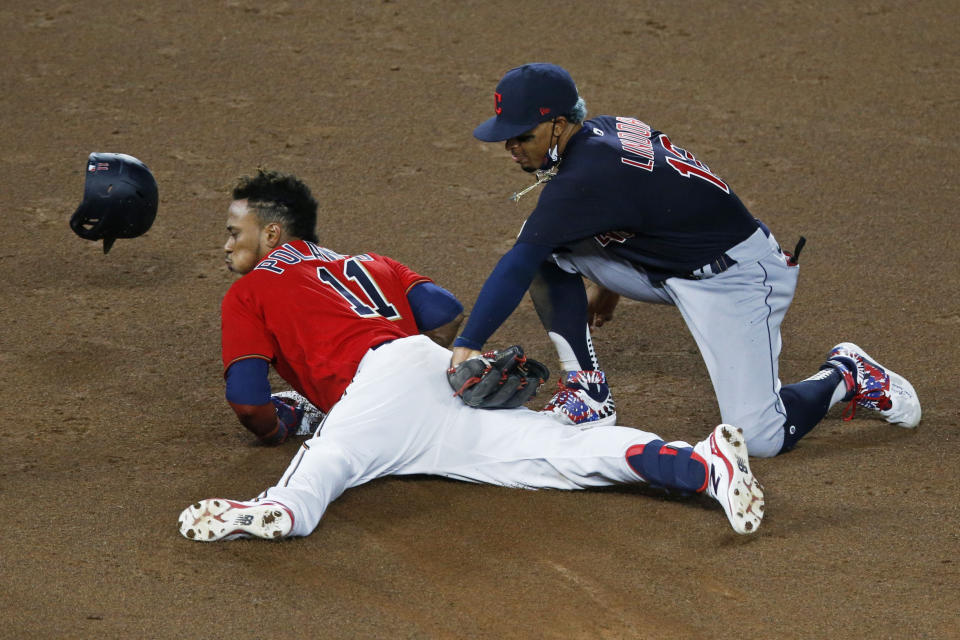 Minnesota Twins' Jorge Polanco, left, beats the tag by Cleveland Indians shortstop Francisco Lindor as he doubles in the fifth inning of a baseball game Friday, July 31, 2020, in Minneapolis. (AP Photo/Jim Mone)