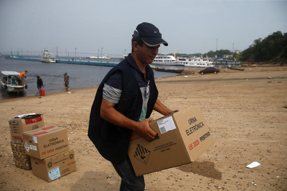 An electoral worker carries an electronic voting machine to be taken by boat to a voting center ahead of tomorrow's elections at the Sao Raimundo port, Manaus, Amazonas state, Brazil, Saturday, Oct.1, 2022. (AP Photo/Edmar Barros)