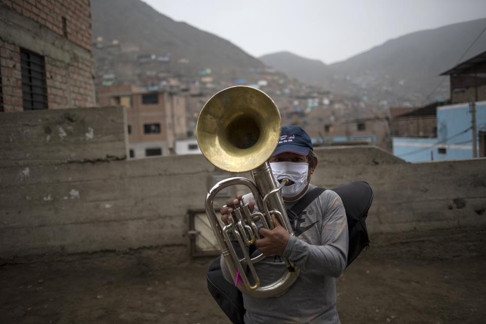 Musician Fernando Herrera plays a brass instrument as he and his band, "Santa Lucia", who have lost their source of income due to restrictions amid the new coronavirus, perform for residents in hopes of monetary donations as they make their way through the Comas district of Lima, Peru, Friday, July 17, 2020. (AP Photo/Rodrigo Abd)