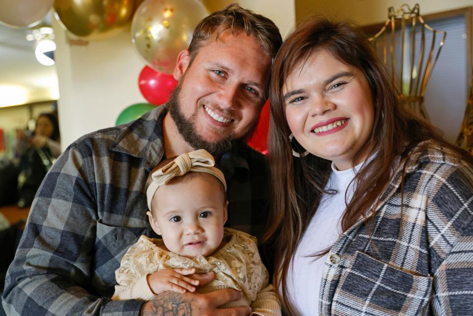 Alan Shurtleff, left, Morgan Shurtleff, right, and their daughter, 1-year-old Cora Dibert, pose for a photo at The Bridge Church, Saturday, Dec. 2, 2023, in Mustang, Okla. When Cora went for a routine blood test in October, the toddler brought along her favorite new snack: a squeeze pouch of WanaBana cinnamon-flavored apple puree. Within a week, the family got an alarming call. The test showed that the 1-year-old had lead poisoning, with nearly four times as much lead as the level that raises concern.