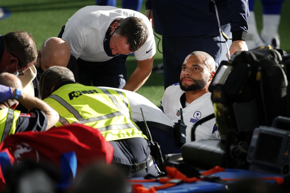 Dallas Cowboys quarterback Dak Prescott, right, looks off as first responders and team medical personnel assist Prescott after he suffered a lower right leg injury running the ball against the New York Giants in the second half of an NFL football game in Arlington, Texas, Sunday, Oct. 11, 2020. (AP Photo/Michael Ainsworth)