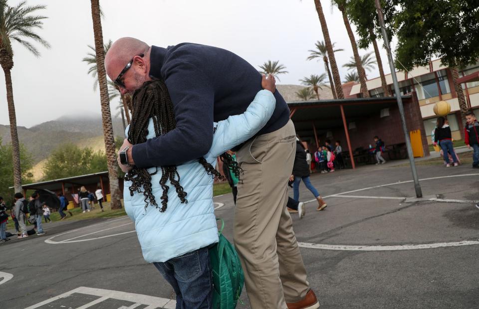 Cahuilla Elementary School principal Dr. Ryan Saunders hugs one of his students after tying her shoe in Palm Springs, Calif., March 30, 2023. 