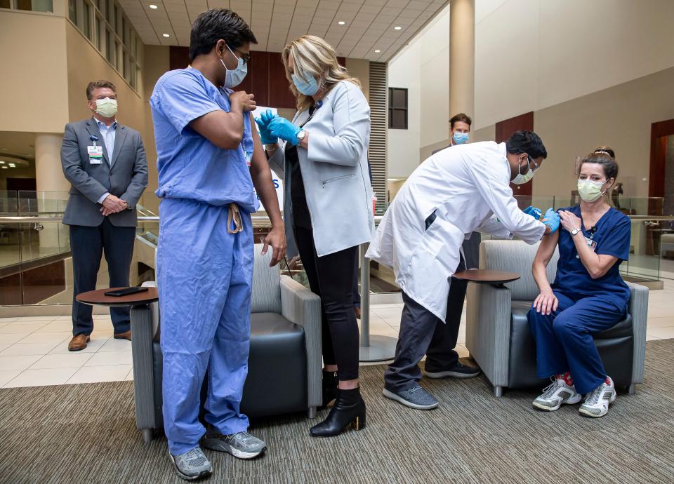 Allison Paul, center, chief nursing officer at HSHS Illinois and HSHS St. John's Hospital, and Dr. Aakash Patel, right, deliver the first doses of the Pfizer COVID-19 vaccine in Sangamon County to Dr. Prashant Jagtap, left, and ICU nurse SallyAnn Tamizuddin at HSHS St. John's Hospital on Dec. 16, 2020, in Springfield. [Justin L. Fowler/The State Journal-Register]