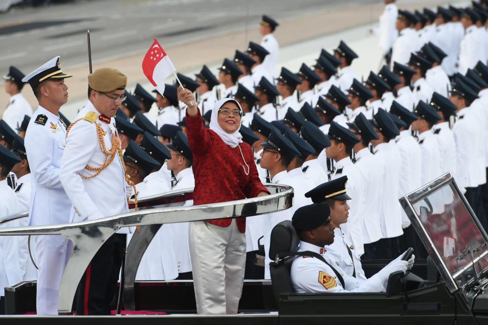 Singapore's President Halimah Yacob (C) waves a Singapore national flag during the 54th National Day Parade in Singapore on August 9, 2019. (Photo by Roslan RAHMAN / AFP)        (Photo credit should read ROSLAN RAHMAN/AFP/Getty Images)