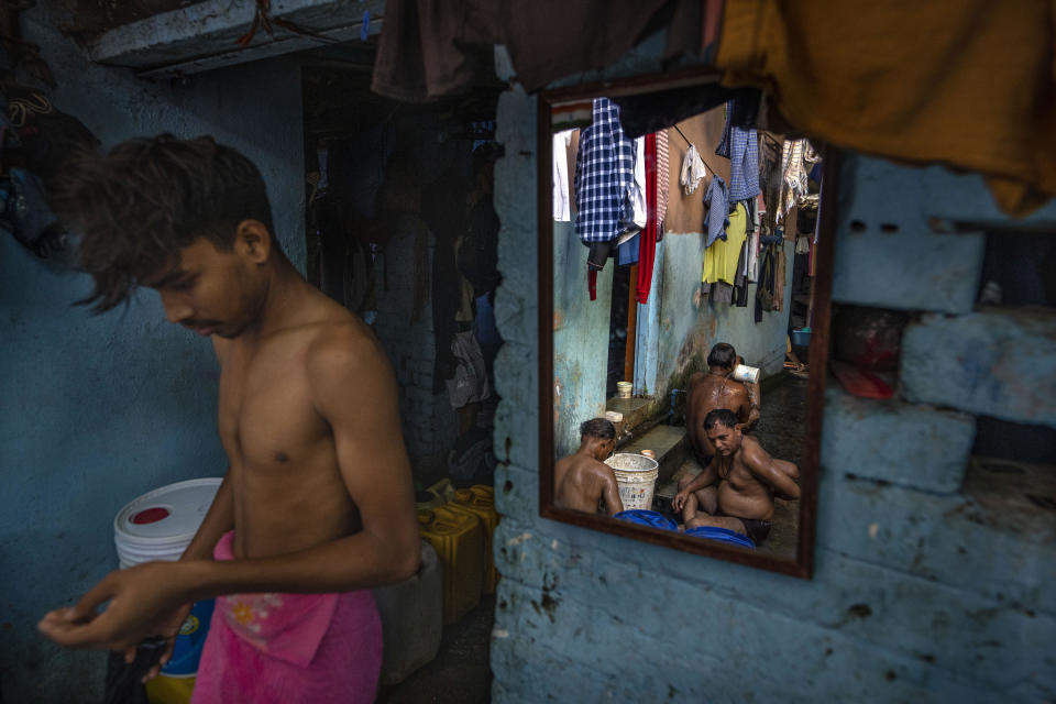 Migrant workers are reflected in a mirror inside a designated bathing area in Dharavi, one of Asia's largest slums, in Mumbai, India, Friday, May 5, 2023. The Indian government has promised that every legal household will soon have plumbing and running water - a goal set for this year that has yet to be reached. "But just because we spend money and put the pipes in, doesn't mean that people will actually have water in their taps," one Indian water expert says. (AP Photo/Dar Yasin)