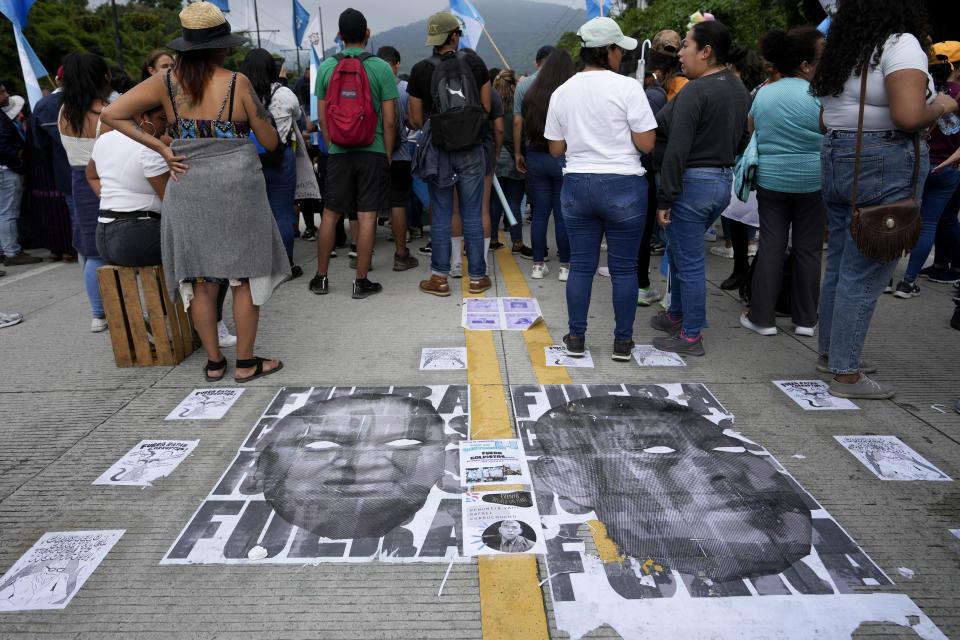 Carteles que representan a la fiscal general Consuelo Porras, izquierda, y al fiscal Rafael Curruchiche se colocan en el suelo mientras los manifestantes bloquean el puente Matasano para exigir su renuncia en Antigua, Guatemala, el sábado 7 de octubre de 2023. Activistas bloquearon carreteras en crecientes manifestaciones para apoyar al presidente electo Bernardo Arévalo luego de que el máximo tribunal de Guatemala confirmó una medida de los fiscales para suspender su partido político por presunto fraude en el registro de votantes. (Foto AP/Moisés Castillo)