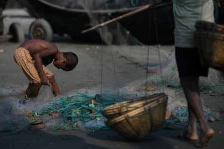 A Rohingya refugee boy scours a fishing net for leftovers on Shamlapur beach in Cox's Bazaar, Bangladesh, March 21, 2018. REUTERS/Clodagh Kilcoyne