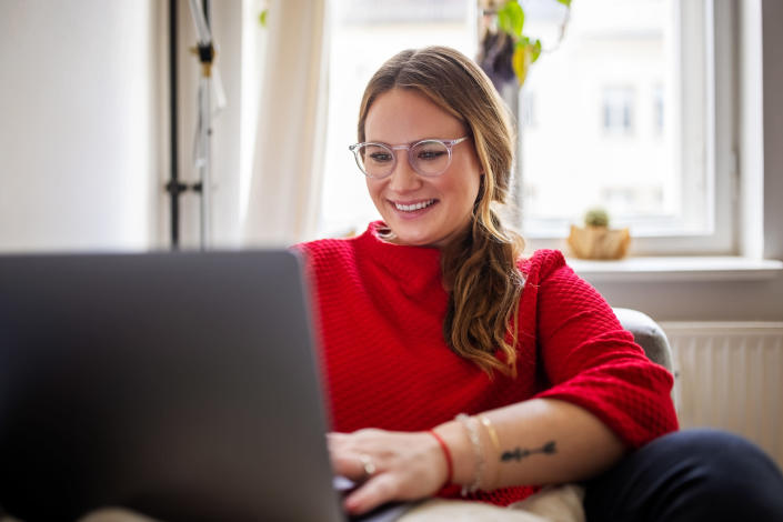 Woman with glasses smiles while working on her computer