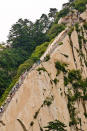 <strong>Mount Huashan Heavenly Stairs, China</strong> With an unknown number of stairs on this ascent (presumably because everyone has always lost count), this is no small feat. After you manage the stairs, you then face a horizontal stretch along three-plank-wide walkway with only a chain to hold onto, flush against the wall of flat rock.