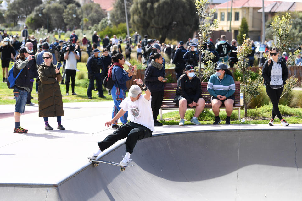 A skateboarder performs a frontside tail slide at the St Kilda skate park as protesters and Victorian Police converge into the area during a rally against mandatory Covid-19 vaccinations in St Kilda, Melbourne, Saturday, September 25, 2021. Source: AAP