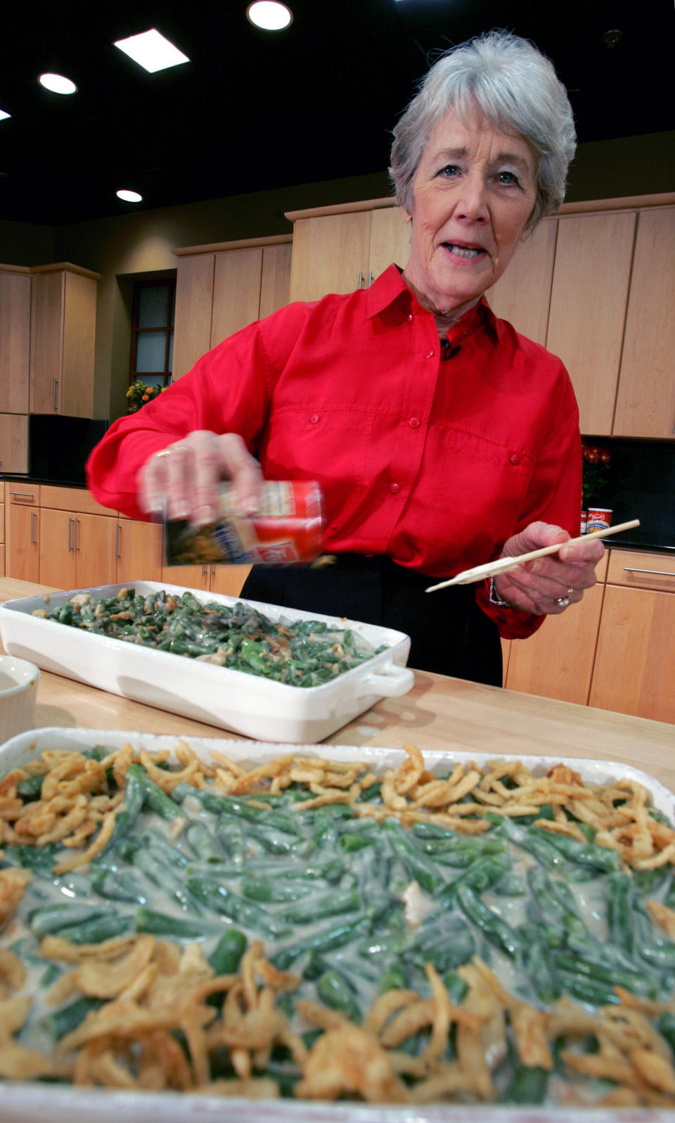FILE - In this Nov. 15, 2005 file photo, a Green Bean Cassorole sits in the foreground as Dorcas Reilly prepares another at the Campbell Soup Co. corporate kitchen in Camden, N.J. Reilly died on Monday, Oct. 15, 2018 and her family will celebrate her life on Saturday, Oct. 27 in the town where she lived, Haddonfield, N.J. Reilly was a Campbell Soup kitchen supervisor in 1955 when she combined green beans and cream of mushroom soup, topped with crunchy fried onions, for an Associated Press feature. It is the most popular recipe ever to come out of the corporate kitchen at Campbell Soup. (AP Photo/Mel Evans, File)