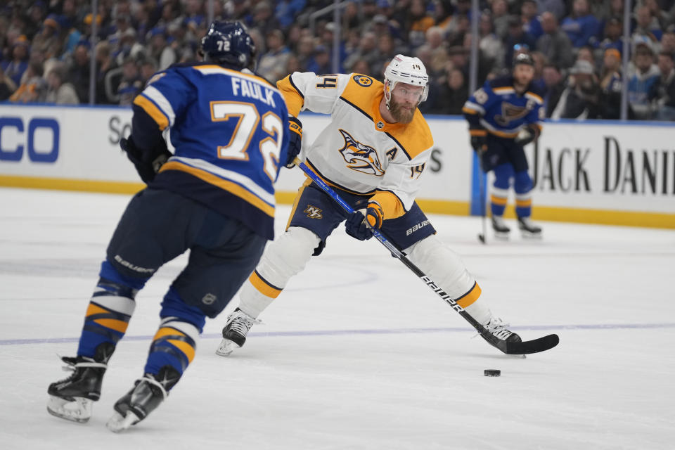 Nashville Predators' Mattias Ekholm (14) brings the puck down the ice as St. Louis Blues' Justin Faulk (72) defends during the first period of an NHL hockey game Monday, Dec. 12, 2022, in St. Louis. (AP Photo/Jeff Roberson)