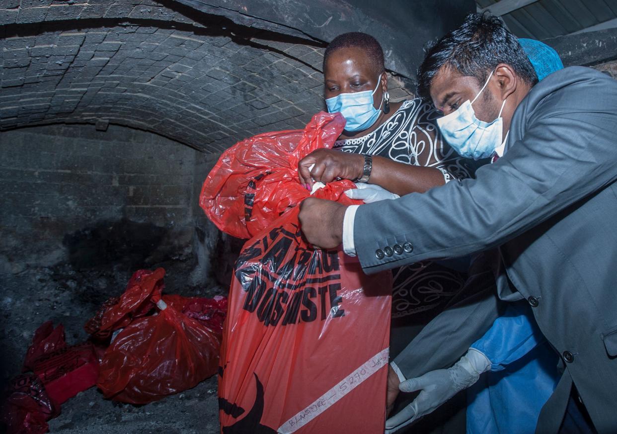 Malawis Health Minister Khumbize Kandodo Chiponda (C) puts packs of expired Covid-19 Astra Zeneca in a pharmaceutical incinerator to destroy them at Kamuzu Central Hospital in Lilongwe on May 19, 2021. - Malawi has destroyed nearly 17,000 doses of the AstraZeneca vaccine that had expired in mid-April, with the health minister blaming 