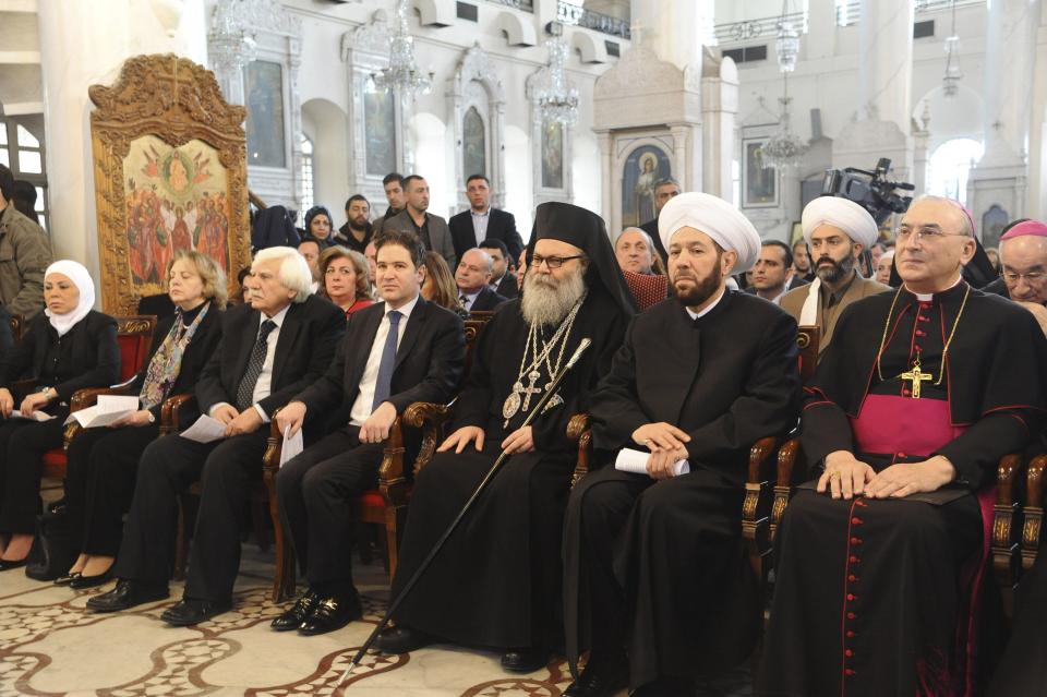 SANA handout shows Greek Orthodox Patriarch John X Yazigi sitting next to Syria's Grand Mufti Ahmed Badr at a ceremony to pray for peace during a Christmas mass at al-Maryamyeh church in Damascus