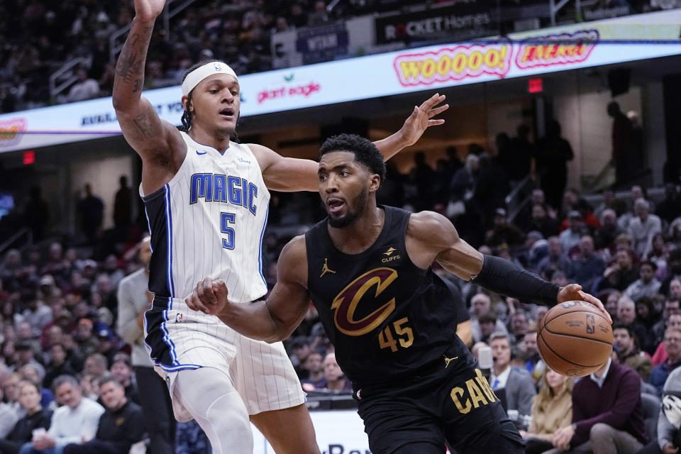 Cleveland Cavaliers guard Donovan Mitchell (45) drives past Orlando Magic forward Paolo Banchero (5) during the second half of an NBA basketball game Wednesday, Dec. 6, 2023, in Cleveland. (AP Photo/Sue Ogrocki)