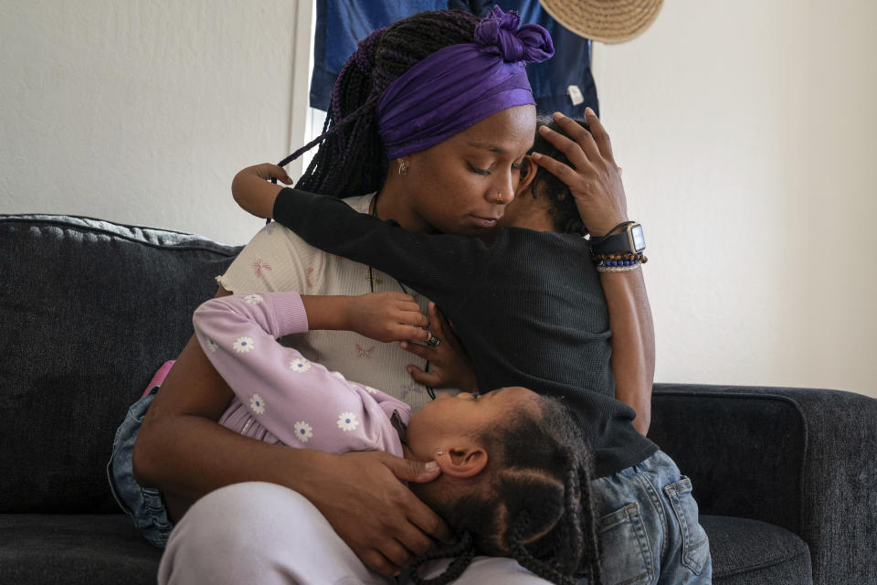 Christina Engram holds daughter, Neveah, left, 6, and son, Choncey, 4, while spending time together at home in Oakland, Calif., on Friday Nov. 24, 2023. (AP Photo/Loren Elliott)