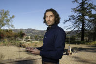 In this Tuesday, Feb. 25, 2020, photo, Jason Meek, whose Northern California wine country home was destroyed in 2017, poses for a photo as he stands in the driveway by the remains of his home in Santa Rosa, Calif. A $13.5 billion settlement between victims, including Meek, of California's catastrophic wildfires and Pacific Gas & Electric was supposed to bring some peace and hope to people still reeling from the devastation. Instead, it has sparked confusion, resentment, suspicion and despair as the victims, government agencies, and lawyers grapple for their piece of the settlement fund. (AP Photo/Eric Risberg)