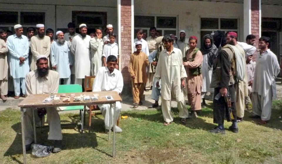 Armed supporters of outlawed militant group Tehreek-e-Taliban Pakistan (right) escort one of three thieves in 2008 (AP)