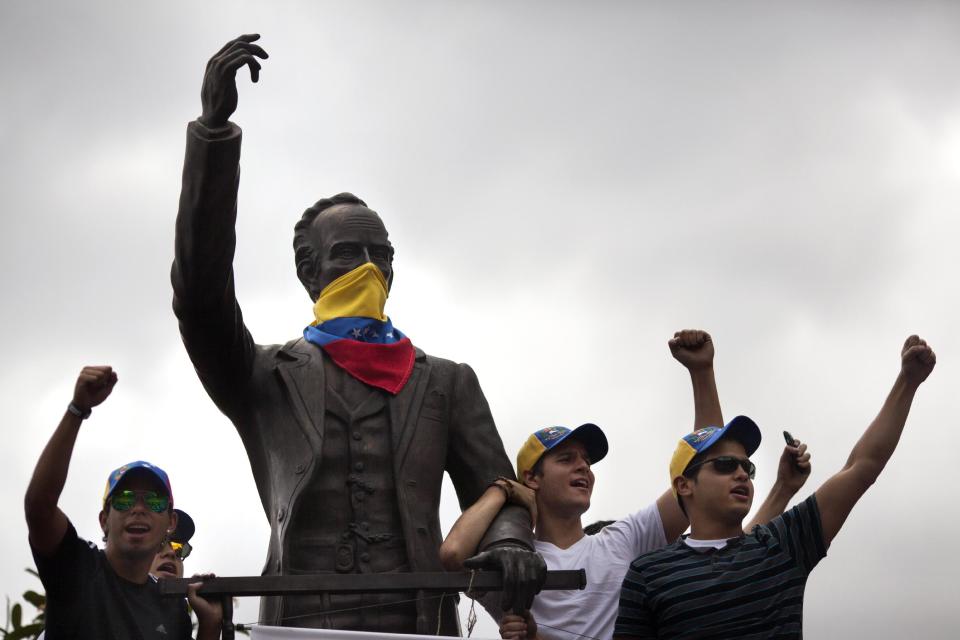 Demonstrators chant anti-government slogans next to a statue of Cuban writer and hero Jose Marti masked with a Venezuelan flag in Caracas, Venezuela, Sunday, March 2, 2014. Since mid-February, anti-government activists have been protesting high inflation, shortages of food stuffs and medicine, and violent crime in a nation with the world's largest proven oil reserves. (AP Photo/Rodrigo Abd)