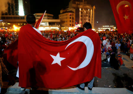Supporters of Turkish President Tayyip Erdogan are covered with a Turkish national flag during a pro-government demonstration on Taksim square in Istanbul, Turkey, July 18, 2016. REUTERS/Ammar Awad