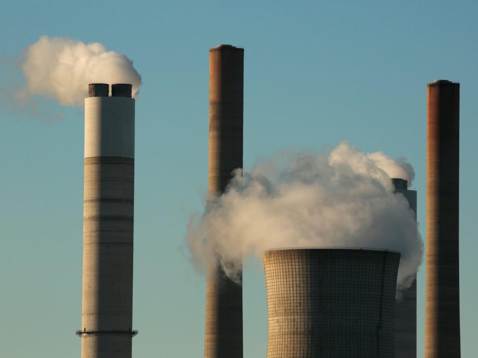smokestacks puff clouds into blue sky at coal fired power plant