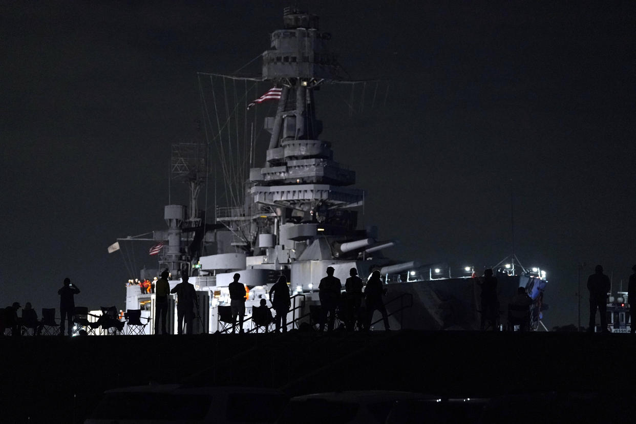 People watch as the USS Texas is moved from the dock Wednesday, Aug. 31, 2022, in La Porte, Texas. The vessel, which was commissioned in 1914 and served in both World War I and World War II, is being towed down the Houston Ship Channel to a dry dock in Galveston where it will undergo an extensive $35 million repair. (AP Photo/David J. Phillip)