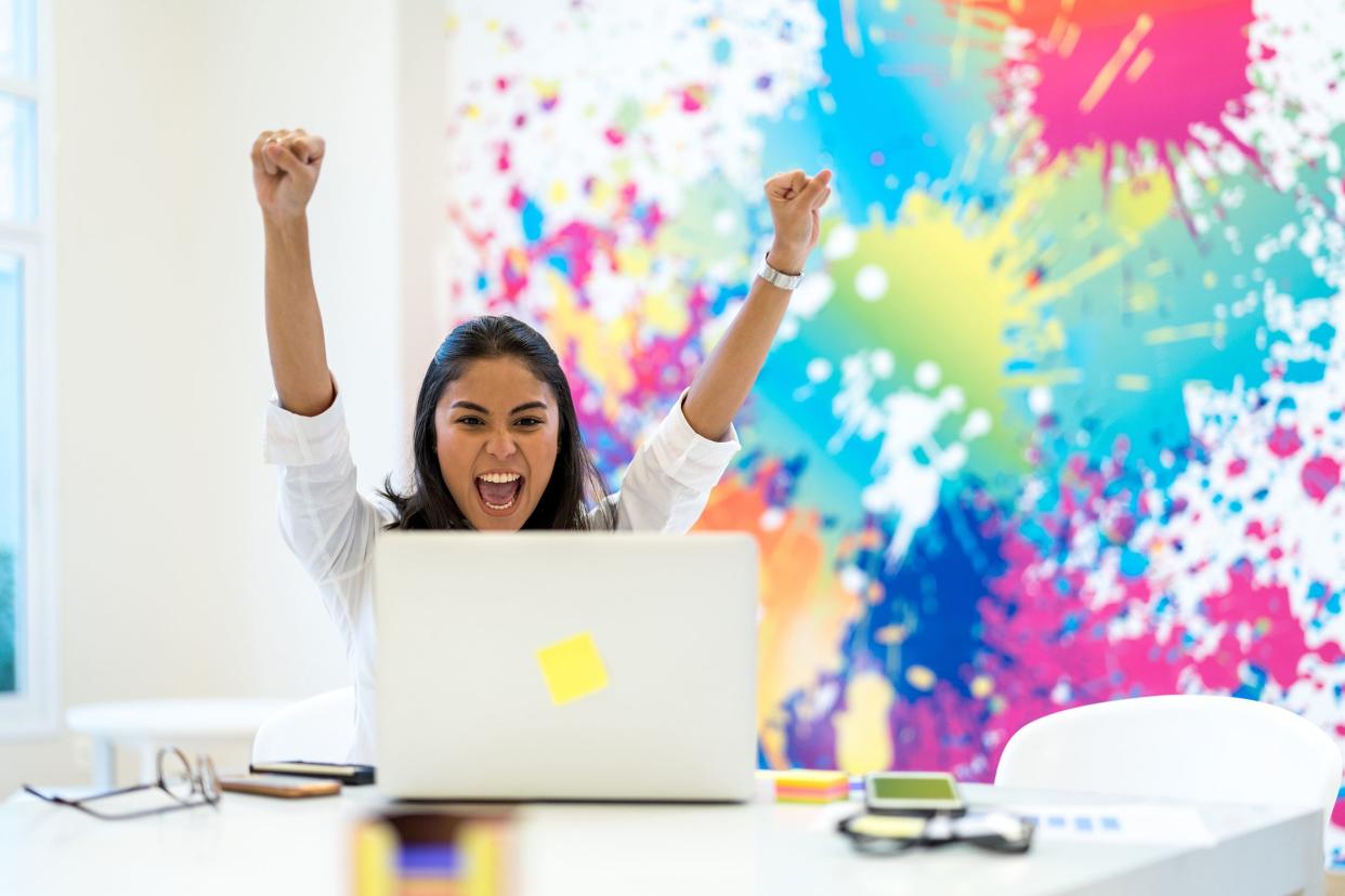 excited Asian woman with her laptop, celebrating at work