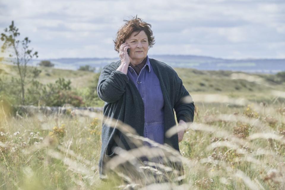brenda blethyn holding a phone in the countryside as vera in television show vera