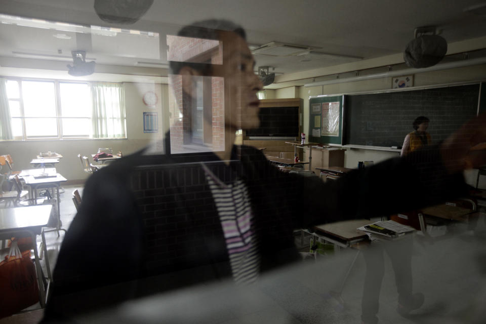 A school faculty member locks a classroom at Danwon High School in Ansan, South Korea, Thursday, April 17, 2014. Several hundred students of the school were among passengers aboard a ferry that sank Wednesday in waters off the southern coast of South Korea. Strong currents, rain and bad visibility hampered an increasingly anxious search Thursday for 287 passengers, many thought to be high school students, still missing more than a day after their ferry flipped onto its side and sank in cold waters off the southern coast of South Korea. (AP Photo/Woohae Cho)